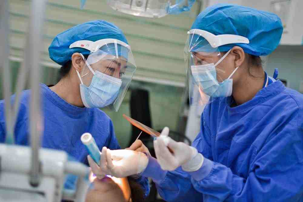 person in blue scrub suit holding pen