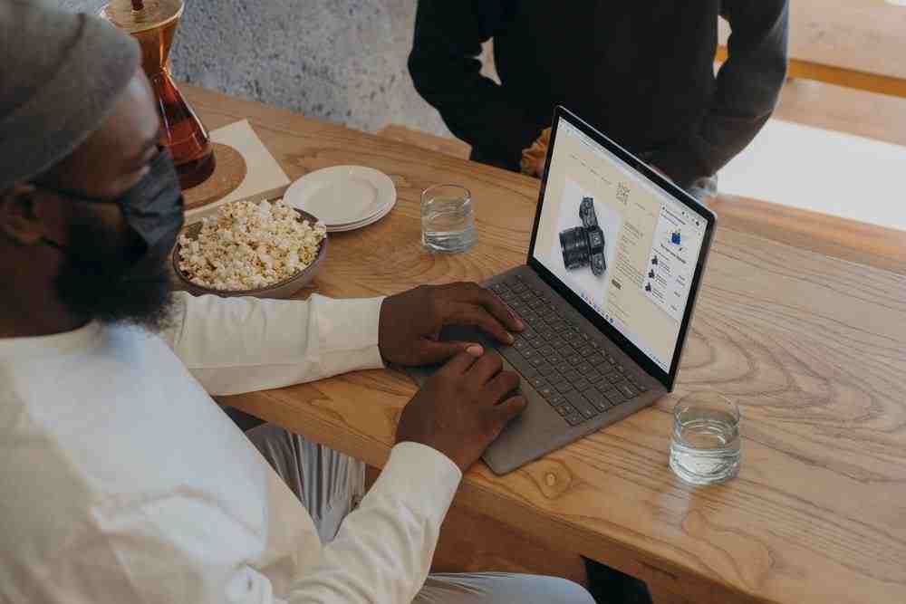 Person sitting on a table on Surface laptop wearing a mask 